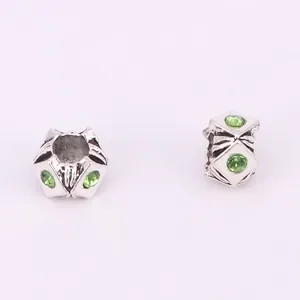 Par de cuentas huecas estilo búho con piedras verdes y textura floral de plata