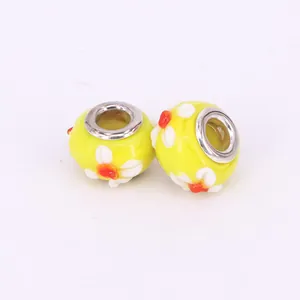 Macro view of yellow glass large hole charm beads with white and orange flower petals