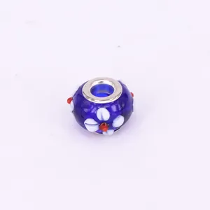 Detailed view of a dark blue glass bead with white floral pattern and silver metal rims