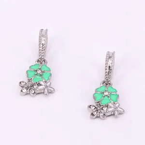 Detail of silver floral earrings with green enamel petals and sparkling rhinestones
