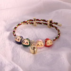 Dettaglio del bracciale in corda multicolore intrecciata con ciondoli smaltati e campanellino