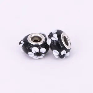 Detailed view of handmade black lampwork glass beads with white 3D floral motifs