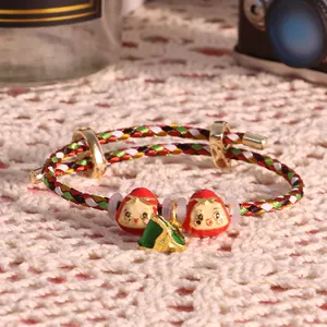 Dettaglio del bracciale colorato con ciondoli Daruma rossi e un pendente zongzi
