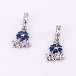 Detail of flower charms with dark blue enamel and white crystals in silver alloy