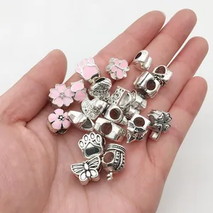 Detailopname van diverse roze emaille bedeltjes voor DIY sieraden in een hand