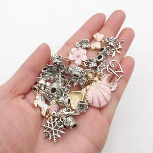 Detailopname van roze emaille bedeltjes met kersenbloesems en eenhoorns voor DIY-sieraden
