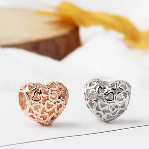 Dettaglio di ciondoli a cuore traforato in oro rosa e argento per bracciali fai-da-te