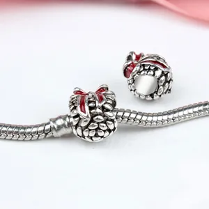 Detailed close-up of retro silver snake chain bracelet with red bow and pinecone charm