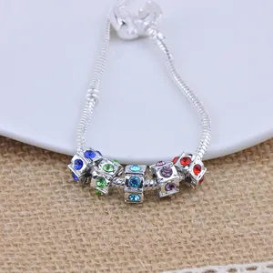 Silver snake chain bracelet featuring five colorful UV diamond cube charms on white plate