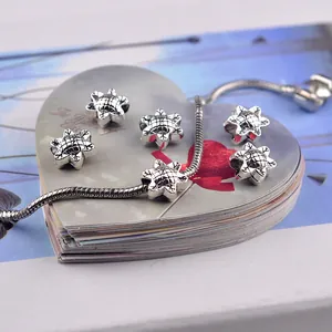 Macro shot of silver sunflower charms and snake chain bracelet for DIY jewelry making