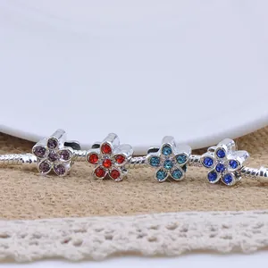 Detailed macro view of silver snake chain bracelet with four colorful floral charms