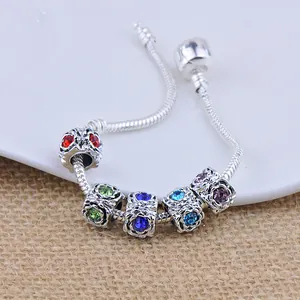 Pandora style snake chain bracelet with five multicolored crystal metal beads on a ceramic plate
