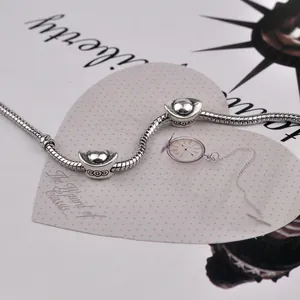 Silver snake chain bracelet featuring traditional Yuanbao charms on vintage paper