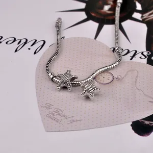 Detailed view of starfish pendants on a silver snake chain bracelet with sea life texture