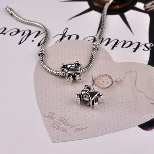 Detail view of silver snake chain bracelet featuring two vintage cartoon girl charms