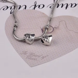 Detailed close-up of a silver snake chain bracelet with heart-shaped hollow charms