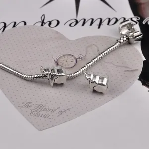 Silver snake chain bracelet featuring detailed elephant charms on a vintage heart card