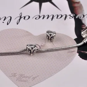 Detailed macro view of vintage owl charms on a silver snake chain bracelet