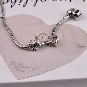 Detailed view of silver snake chain bracelet featuring hollow butterfly beads on a gift card