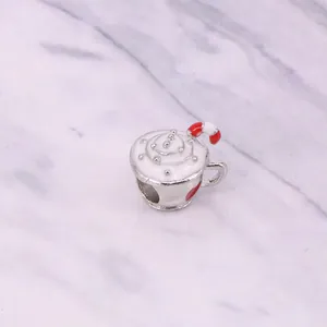 Macro shot of silver coffee cup charm with white cream and red striped straw for DIY jewelry