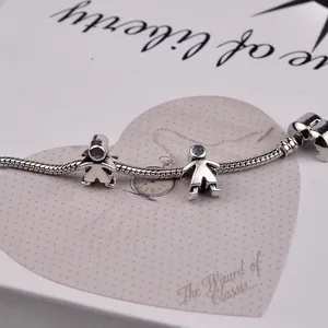 Detailed view of silver snake chain bracelet with boy and girl pendants on a gift card
