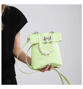 Detailed view of mint green handbag featuring a silver bow buckle and pearl handle strap