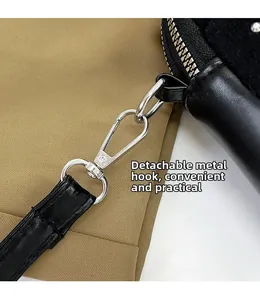 Detail of detachable metal hardware hook and zipper on a black leather crossbody bag
