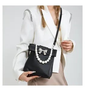 Close-up of black leather bag with silver bow buckle and elegant pearl handle strap