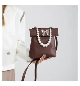 Detailed shot of dark brown bag with silver bow ornament and elegant pearl handle