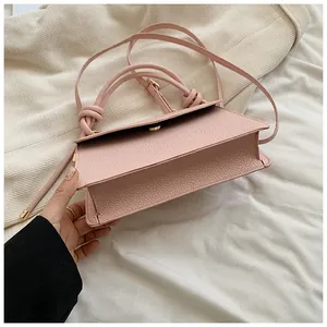 Macro detail of the pink pebbled leather handbag with stylish knotted handle and strap