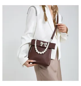 Detail of dark brown leather handbag featuring pearl handle and silver bow decoration