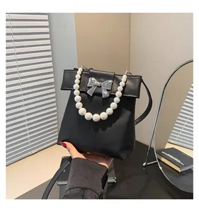 Close-up of elegant pearl handle and silver bow buckle on black matte leather bag