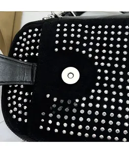 Macro detail of silver magnetic snap button on black rhinestone encrusted crossbody bag