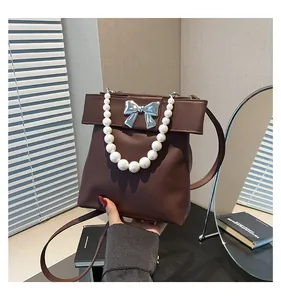 Close-up of dark brown PU leather handbag featuring a large bow and pearl handle detail
