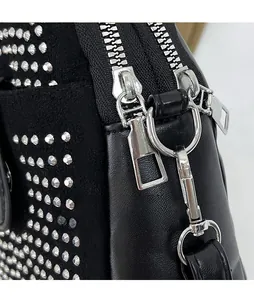 Detail of silver double zippers and metal studs on black leather crossbody bag