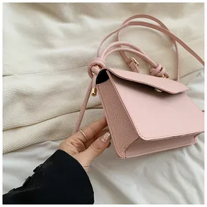 Detail view of pink pebbled leather small crossbody bag with a gold buckle and knotted strap