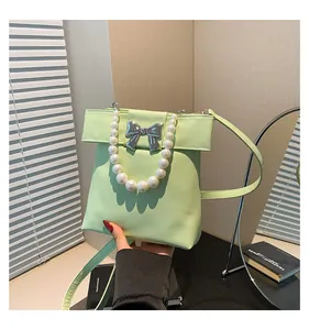Detail of mint green handbag featuring pearl handle and silver bow metal ornament