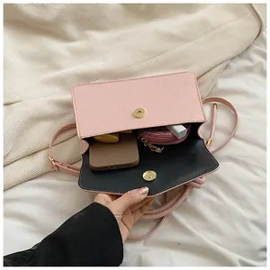 Detail view of pink crossbody bag interior showing storage space for phone and lipstick