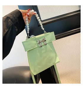 Detail of mint green handbag with pearl handle and silver metal bow ornament