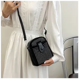 Close-up of small black leather crossbody bag with silver studs on white lace dress
