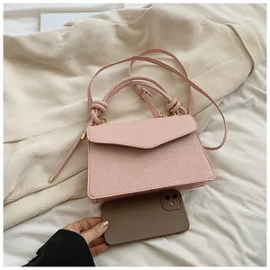 Close-up of pink pebbled leather small crossbody bag showing compact size near a phone