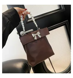 Detail of brown leather bag with pearl handle and large bow with silver buckle