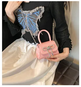 Detail van roze mini-handtas met zilveren strass-strik en metalen ketting schouderriem