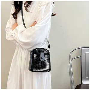 Detail of a mini black crossbody bag featuring silver metal studs and a snap closure