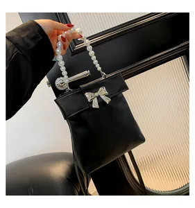 Detail of elegant black handbag featuring a large pearl handle and silver bow buckle charm