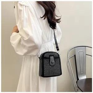 Detailed view of a black mini crossbody bag with silver rhinestones on a white dress