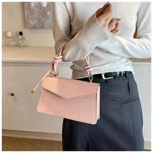 Detailed shot of pink lychee leather handbag with knotted handle and golden ring hardware