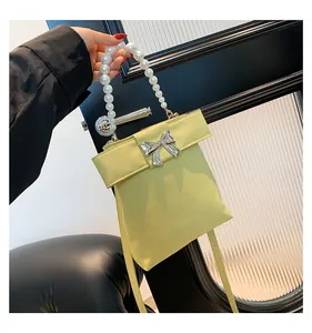 Detail of light yellow satin pearl bag with silver bow accent and beaded handle