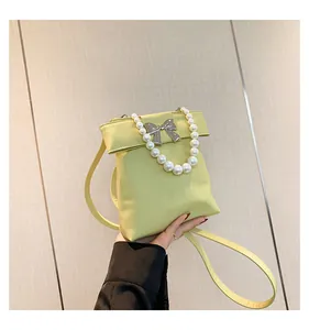 Close-up of lemon yellow bag featuring silver bow accent and white pearl handle