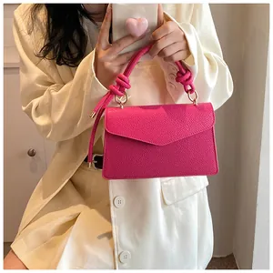 Detail of fuchsia leather handbag with knotted handle and elegant gold metal rings